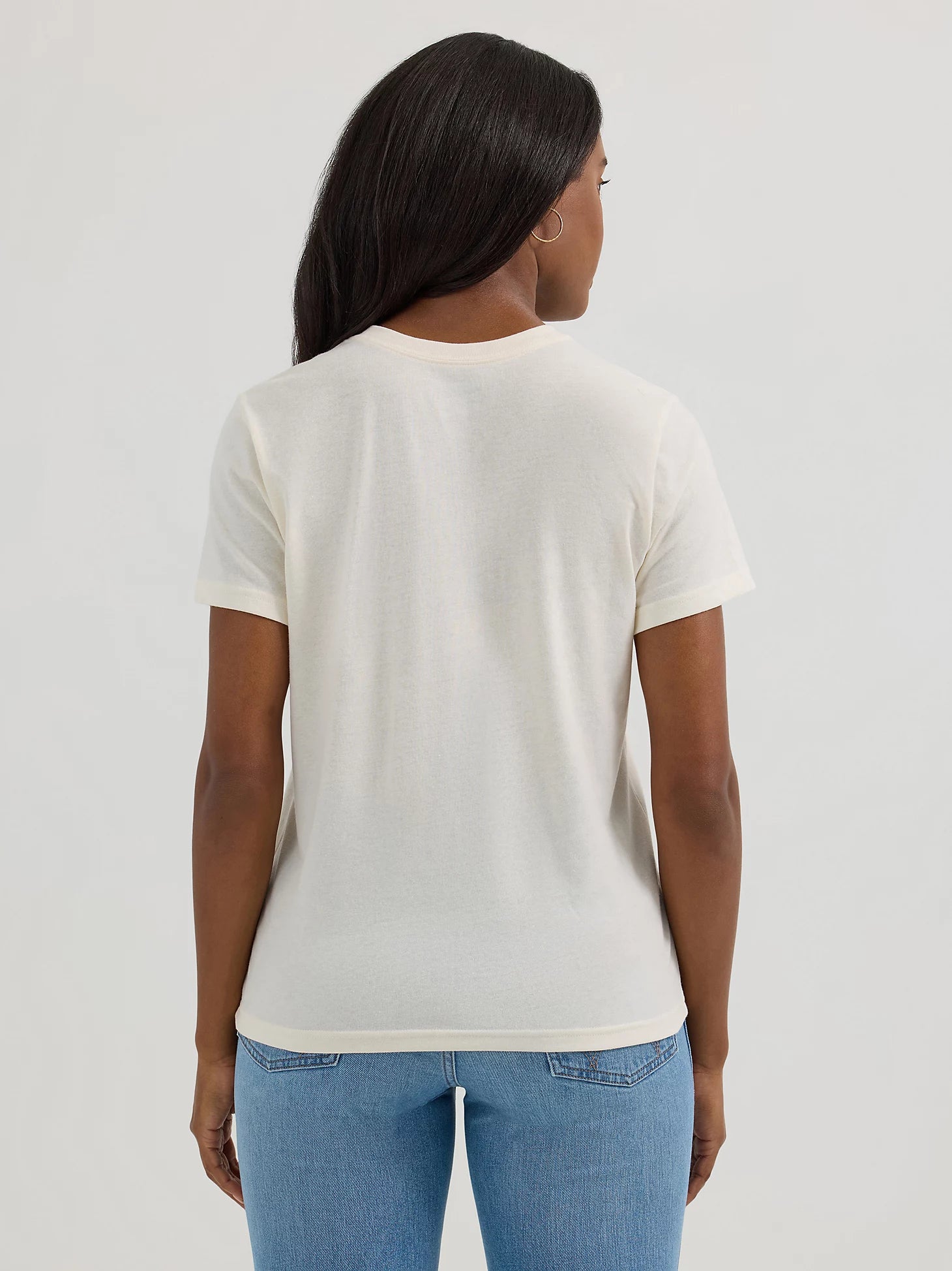 Person wearing a plain white t-shirt and blue jeans on a light gray background