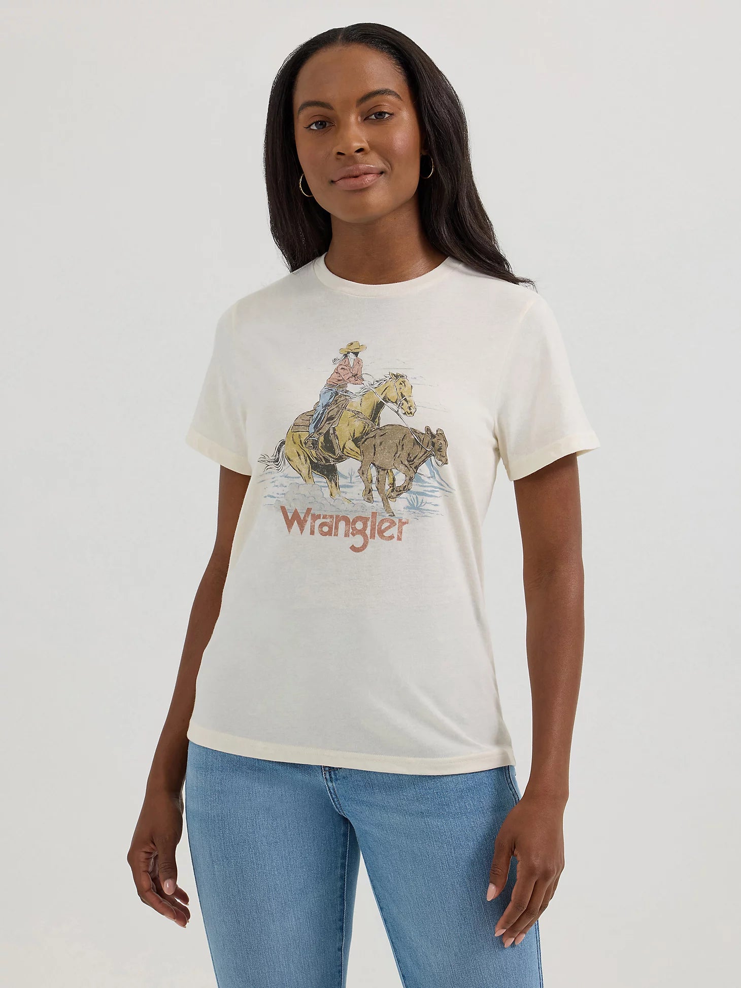 Woman wearing a white t-shirt with a graphic design and 'Wrangler' branding.